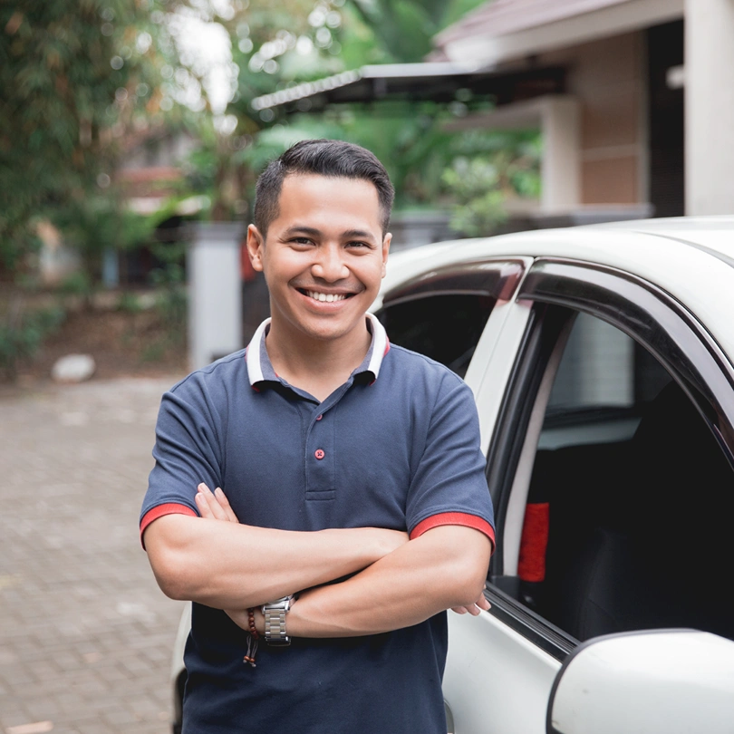 man smiling in front of his car